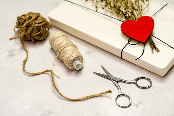 Gift box made of kraft paper, tied with lace. A wooden red heart - Valokuva, kuva