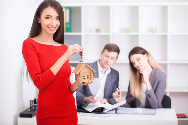 Alegre agente de bienes raíces dando llave de la casa a los propietarios felices, youn
 - Foto, imagen