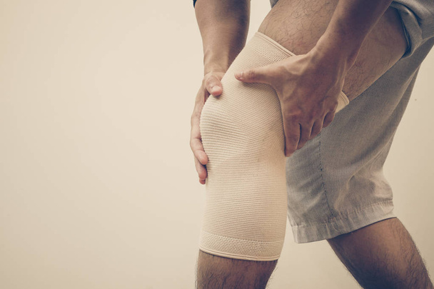 Hombre que usa un soporte de rodilla para curar la rodilla débil o lesionada
 - Foto, Imagen