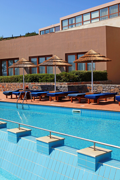 Junto a la piscina con cama de piscina y sombrilla en un resort de lujo
 - Foto, Imagen