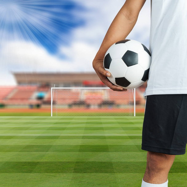 Joueur de football tenant un ballon dans un terrain de football
 - Photo, image