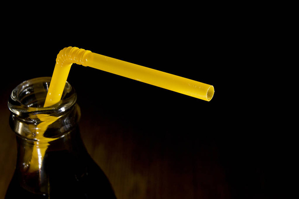 De hals van een fles cola met een rietje - Foto, afbeelding