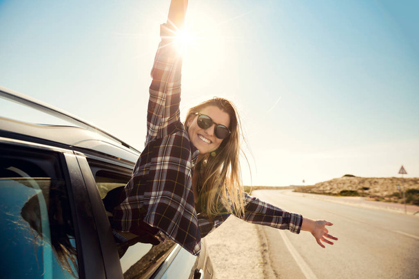 Beautiful woman looking out the car window with open arms enjoying the sunshine - Foto, Imagen