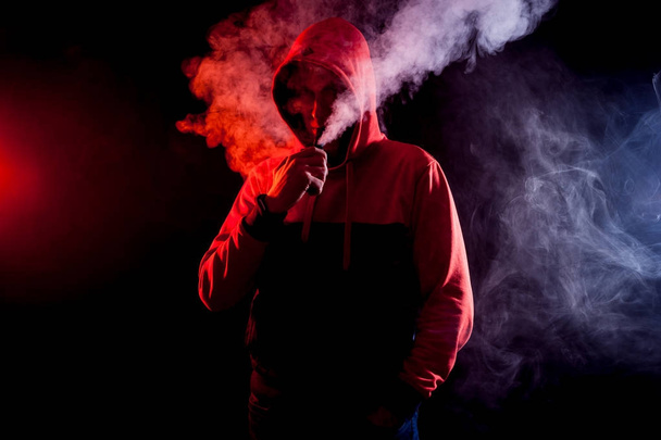 der Mann raucht eine elektrische Zigarette auf dem hellen Hintergrund - Foto, Bild