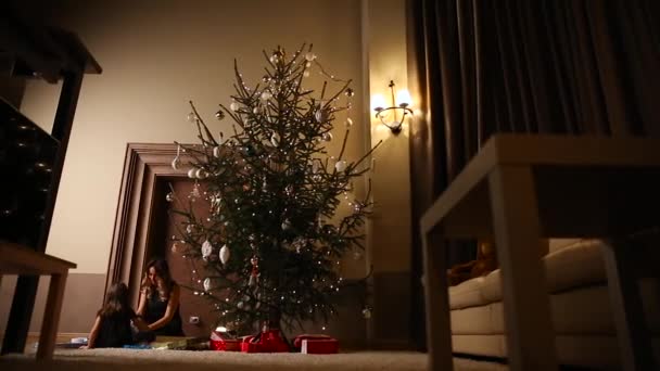 Μαμά και κόρη Απελευθερώστε το χριστουγεννιάτικο δώρο κορδέλες κάτω από το δέντρο στο σαλόνι του σπιτιού τους - Πλάνα, βίντεο