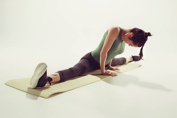 Hermosa morena delgada haciendo algunos ejercicios de estiramiento en un gimnasio
 - Foto, Imagen