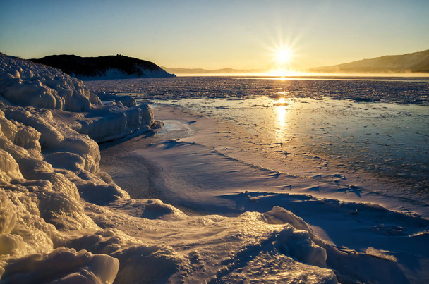 Ice floes floating on the fog water in the lake Baikal and hill. Sunset - Фото, изображение