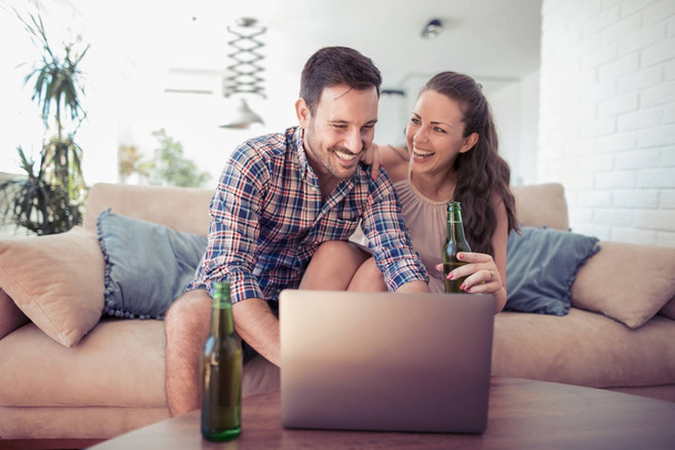 Onnellinen nuori pari kannettavalla tietokoneella kotona
. - Valokuva, kuva