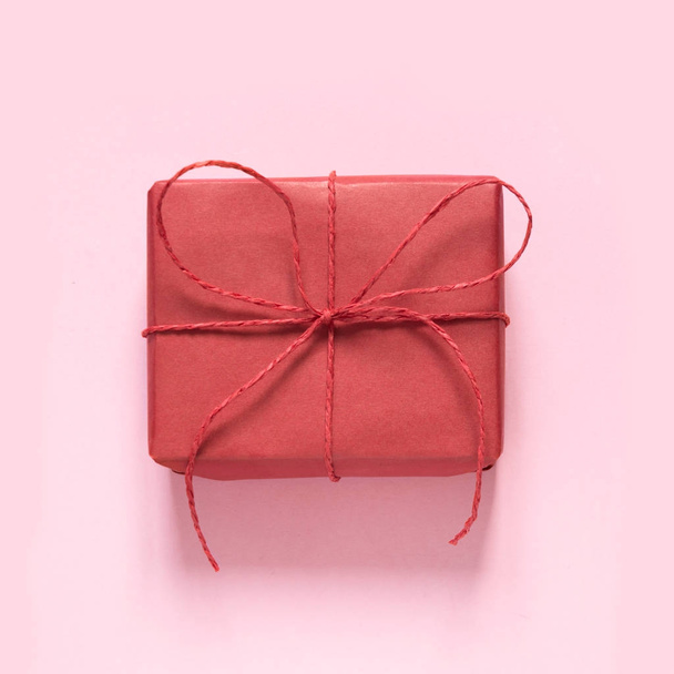 Valentine's card. Red gift with bow of rope on pastel pink background. Top view. - Photo, image