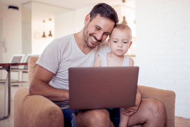 Család, apaság, technológia és az emberek koncepció-boldog apa és kisfia, tabletta pc számítógép otthon a karosszékben ül. - Fotó, kép