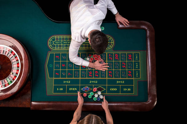 Mann Croupier und Frau spielen Roulette am Tisch im Casino. Draufsicht an einem Roulettetisch mit Maßband. - Foto, Bild