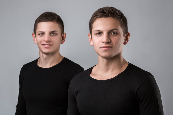 I due fratelli gemelli stanno sullo sfondo grigio
 - Foto, immagini