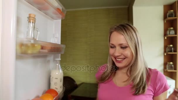 A woman pulls out fruit from the refrigerator. - Video