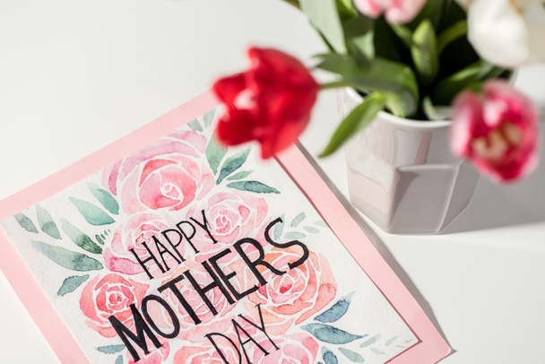 close-up view of happy mothers day card and tulips in vase on white - Foto, imagen