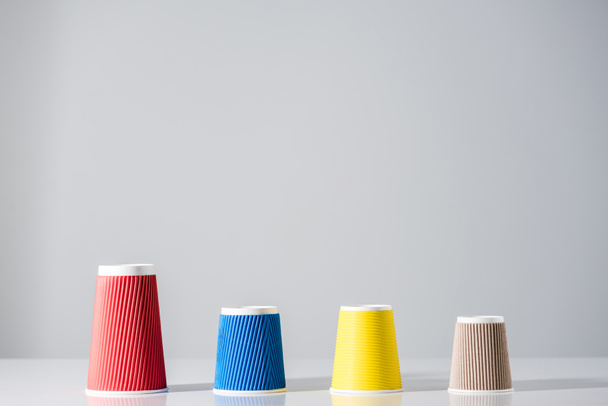 various colorful paper cups in a row on grey  - Foto, Bild