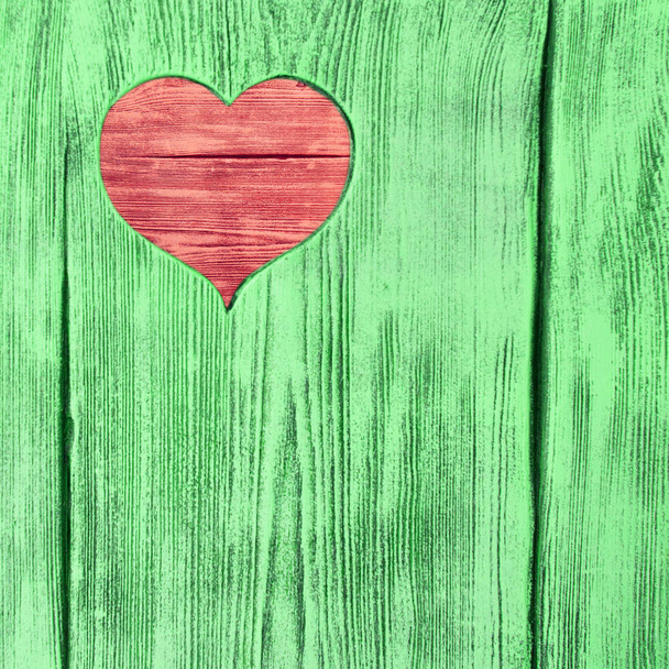 Red heart carved in a green wooden board. Background. - Foto, Bild