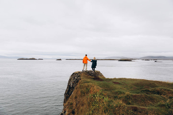 崖から海の眺めを楽しんでいるカップルの背面図 - 写真・画像