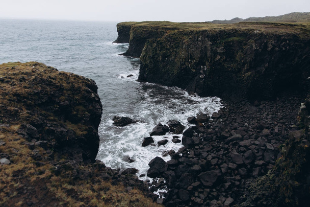 Морський пейзаж зі скелею, камінням і неслухняними хвилями
 - Фото, зображення