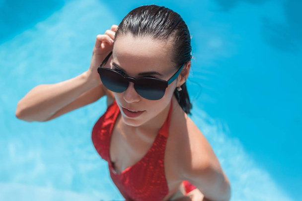 high angle view of young wet woman in swimsuit at swimming pool - Photo, image