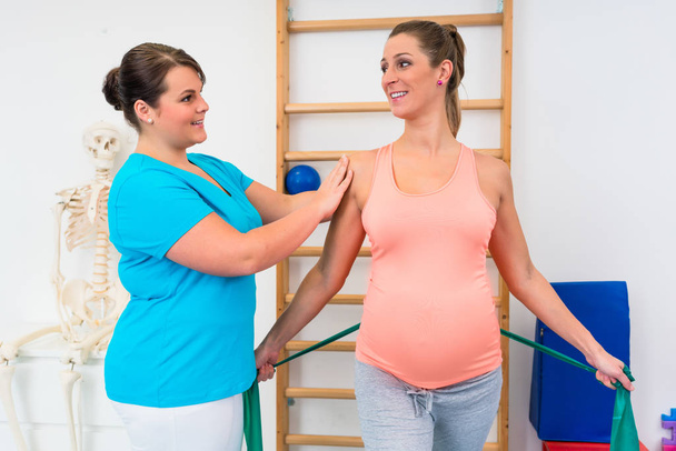 Mujer embarazada haciendo ejercicio con fisioterapeuta y resistanc
 - Foto, imagen
