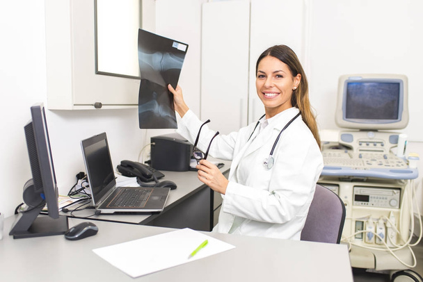 Женщина-врач смотрит на рентгеновское изображение пациента в хосписе
 - Фото, изображение