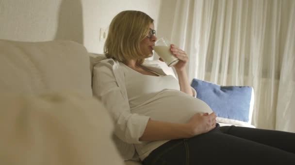 pregnant woman drinking milk at home - Filmati, video