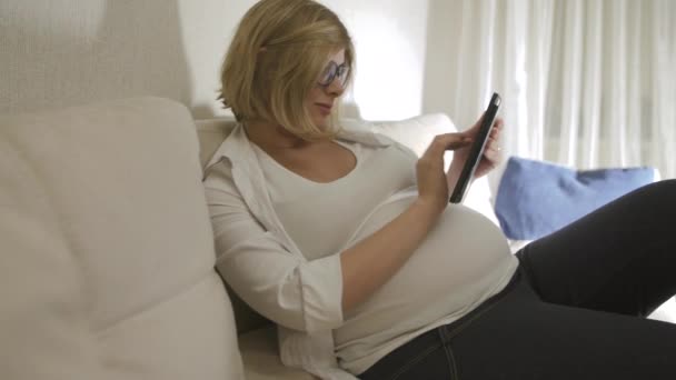 pregnant woman at home with phone - Filmati, video