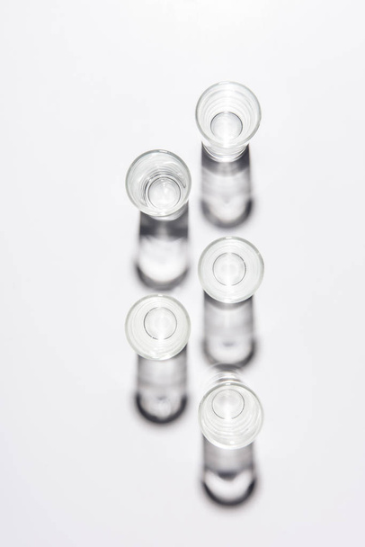 top view of five small empty glasses on white table - Фото, зображення