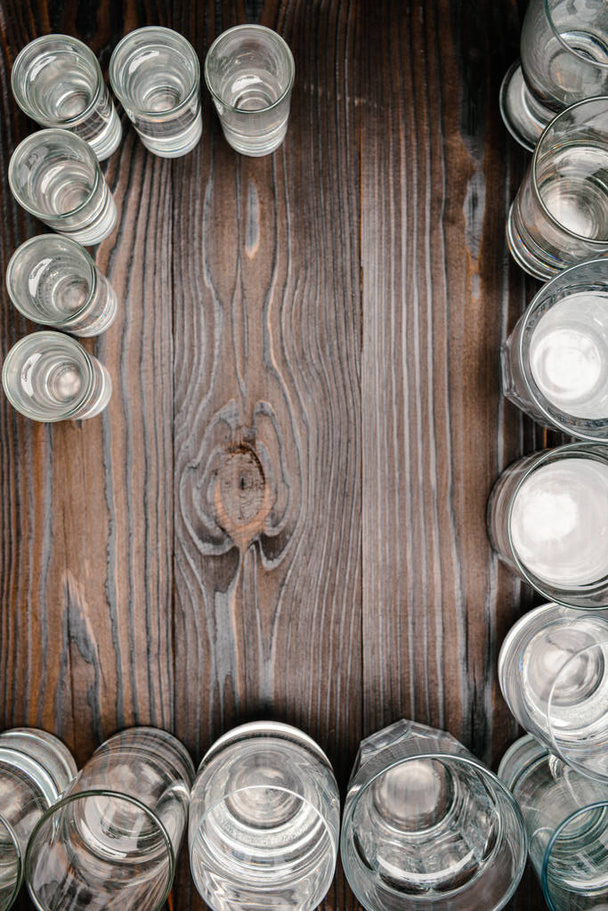 вид сверху на стаканы разного размера с водой на деревянном столе
 - Фото, изображение