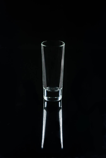un pequeño vaso sobre superficie reflectante negra
 - Foto, Imagen