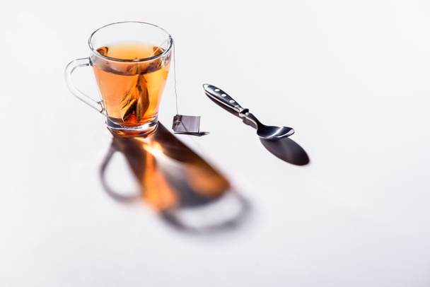 glass cup of black tea and spoon on table - Foto, afbeelding