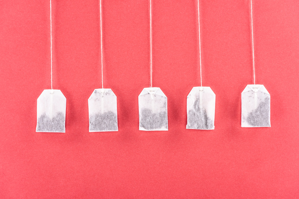 top view of five unused tea bags isolated on red - Photo, Image