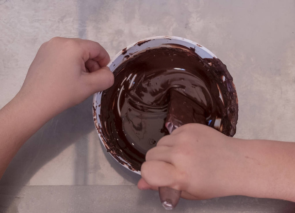 mains d'un enfant jouent le chef pâtissier mélangeant le chocolat dans un bol
 - Photo, image