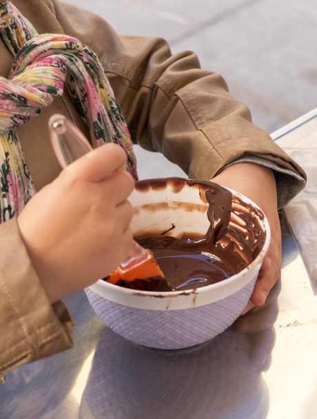 le mani di un bambino giocano il pasticcere che mescola il cioccolato in una boccia
 - Foto, immagini