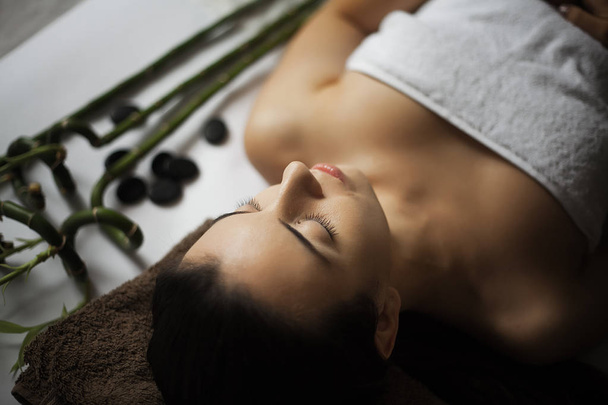 Imagen de la mujer en el salón de spa tumbada en el escritorio de masaje
 - Foto, imagen
