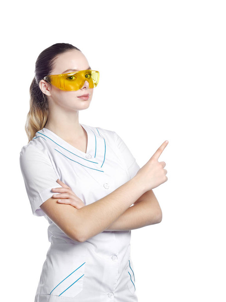 Beautiful girl in protective yellow glasses in a medical suit. - Фото, зображення