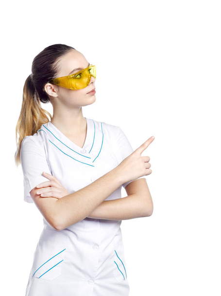 Beautiful girl in protective yellow glasses in a medical suit. - Foto, imagen