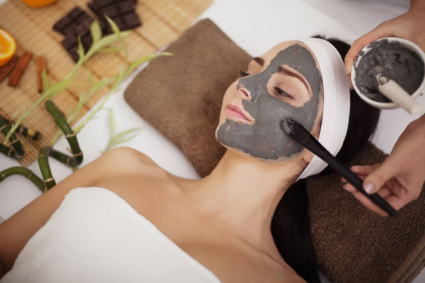 Masaje spa para mujer joven con mascarilla facial en la cara - en interiores
 - Foto, imagen