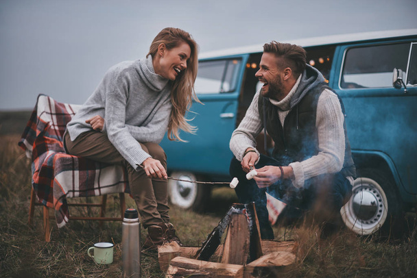 laughing tourist couple roasting marshmallows over a campfire  - Valokuva, kuva