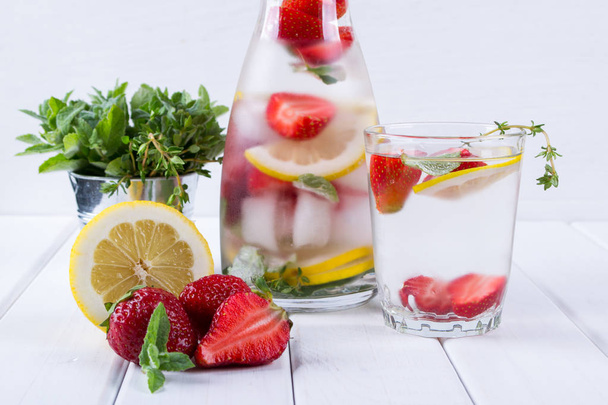 Mineralwasser mit Erdbeeren, Eis, Kräutern und Minzblättern auf weißem Hintergrund, hausgemachtes Entgiftungssodawasser-Rezept. - Foto, Bild
