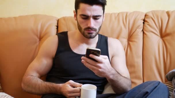 Young man talking on phone while drinking coffee - Footage, Video