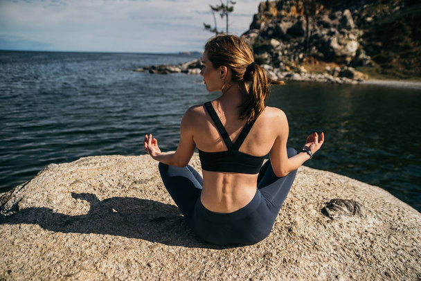 Young woman is practicing yoga at mountain lake - Foto, Imagem