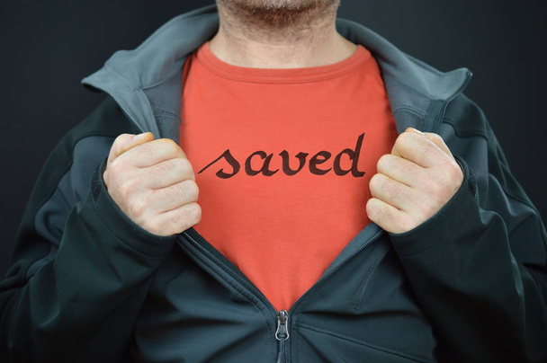 ένας άνδρας με τη λέξη αποθηκεύονται γραμμένο στο κόκκινο t-shirt του δείχνει κατά το άνοιγμα το σακάκι του με τα δύο χέρια - Φωτογραφία, εικόνα