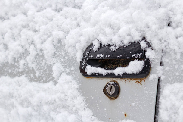 Snow covered car door handle closeup. Cars in winter - Foto, afbeelding