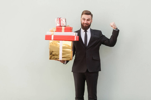 smiling businessman holding gift boxes on grey background  - Fotoğraf, Görsel