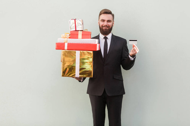 smiling success businessman holding gift boxes and credit card - Foto, Bild