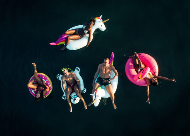 Happy people partying with animal and fruit shapes mats, view from above - 写真・画像