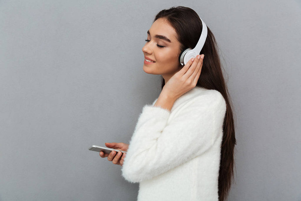 Side view of smiling brunette woman in sweater and headphones - Fotoğraf, Görsel