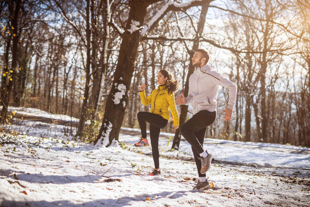 スポーツ ウエア冬雪公園、屋外で、ジョギングする前に、のウォーミング アップでスポーティな若いカップルのトレーニング - 写真・画像