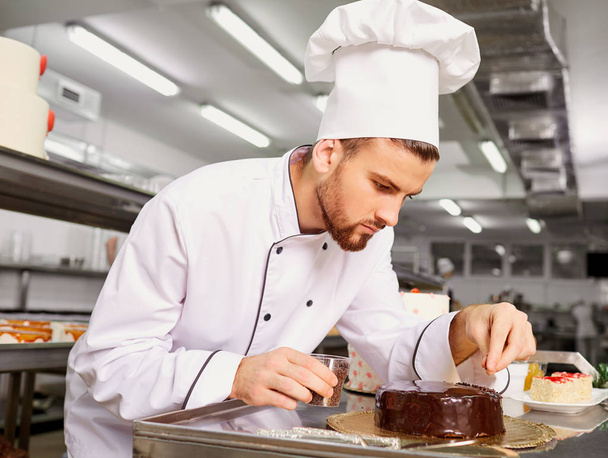 Man confectioner with a cake in his hands in the pastry. - Foto, afbeelding